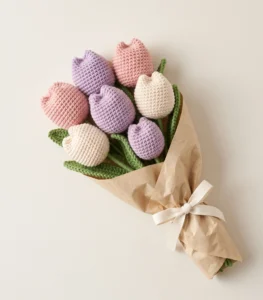 Seven-flower crochet tulip bouquet in pink, lavender and cream, wrapped in kraft paper with a cream ribbon
