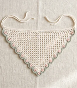 Ivory floral crochet bandana with sage-green scalloped edging, blush-pink flowers and ivory ties